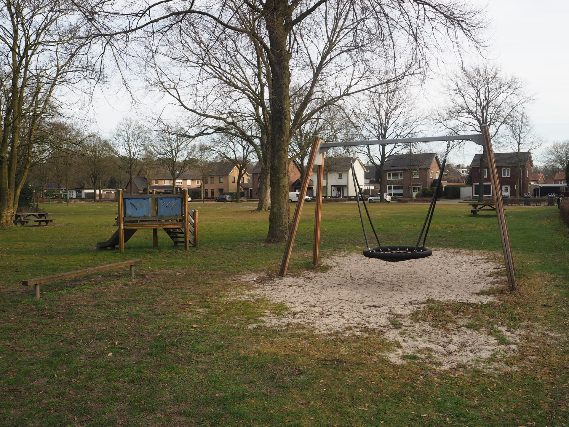 Enlarged image: on the left a climbing frame with slide, on the right a swing. In the background are houses.