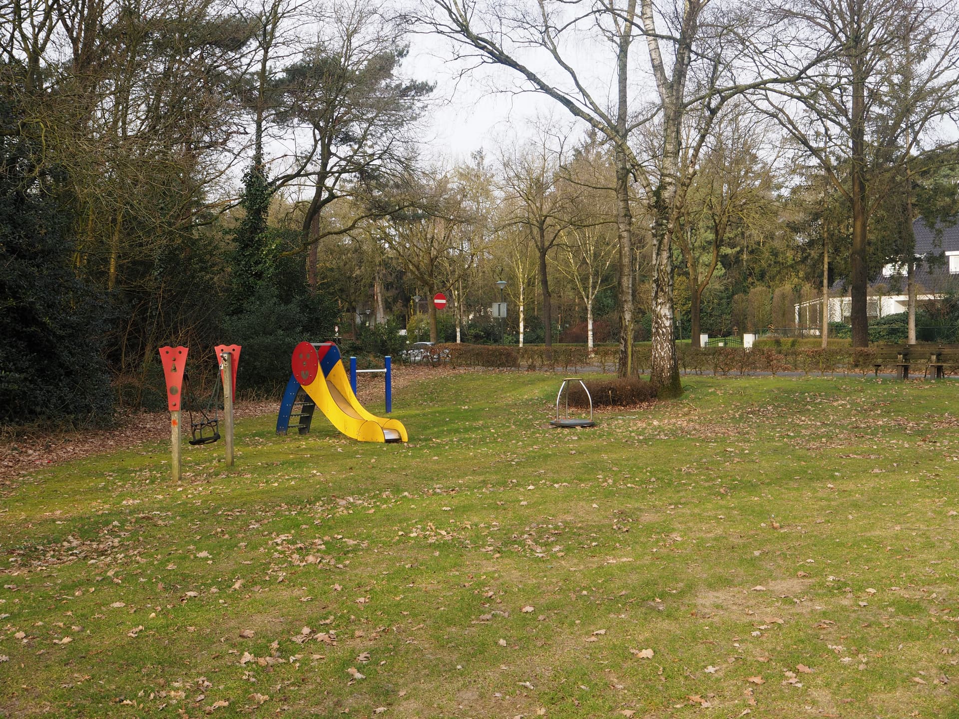 Enlarged image: on the left side playground equipment with a slide to its right. In the background are trees.