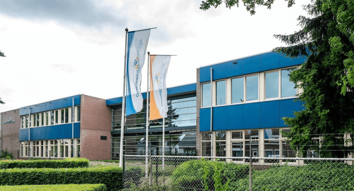 Enlarge picture: the school building with the school flags in front of it.
