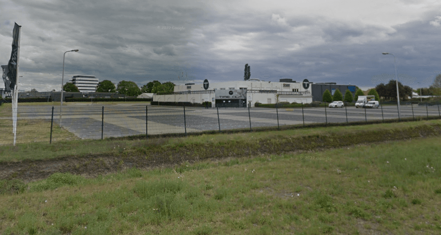 Enlarge image: the Time Out building with the parking lot, a fence and the berm in front of it