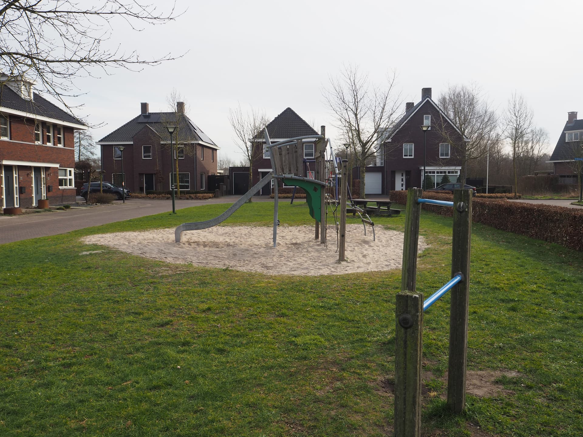 Enlarge image: a tumble frame and climbing apparatus with slide with homes in the background